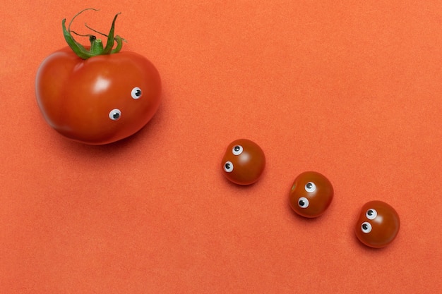 Tomaten mit lustigem Konzept der Augen, Kopienraum. Drei frische kleine Kirsche