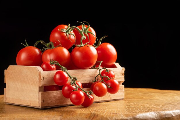 Tomaten, schöne Tomaten, die in einer Holzkiste über rustikalem Holz angeordnet sind, selektiver Fokus.