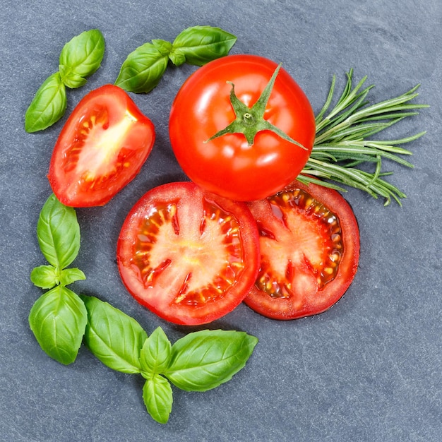 Tomaten Tomaten Gemüse mit Basilikum quadratisch von oben auf einer Schiefertafel