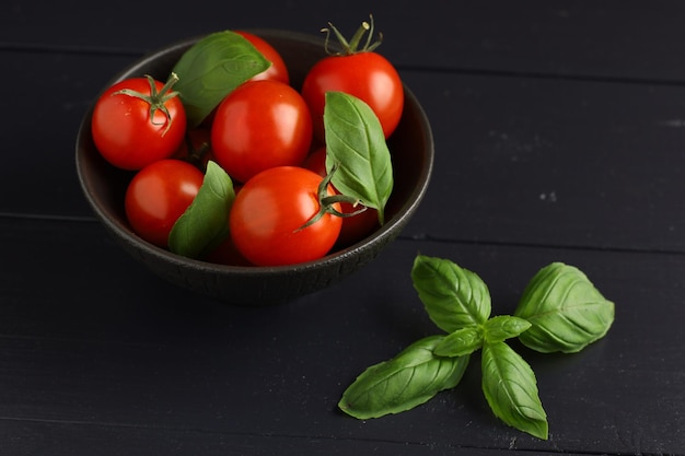 Tomaten und Basilikum in einer Schüssel Frische Kirschtomaten auf einem Teller und Basilikumblättern