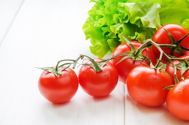 Foto tomaten und grüne salatblätter auf weißem hintergrund