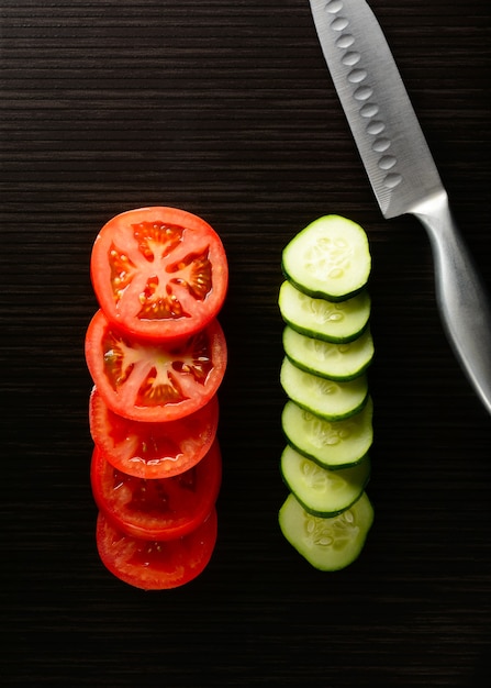 Tomaten und Gurken mit einem Messer schneiden