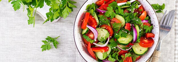 Tomaten- und Gurkensalat mit roter Zwiebel, Paprika, schwarzem Pfeffer und Petersilie Veganische Nahrung Diätmenü Top-View Flachlag