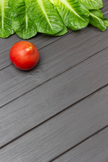 Tomaten- und Salatblätter auf dunklem Holzhintergrund