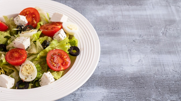 Tomaten, Wachteleier, Salat, Käse und schwarze Oliven auf einem Teller. Gesundes und Diät-Lebensmittelkonzept. Speicherplatz kopieren