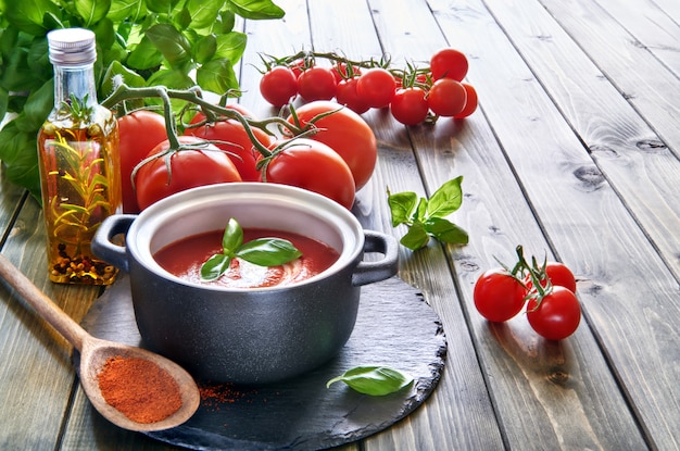 Tomatencremesuppe in schwarzer Keramikpfanne mit Sahne und Basilikum