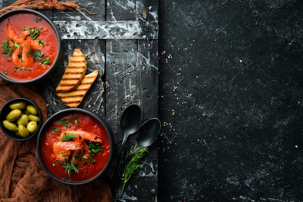 Tomatencremesuppe mit Garnelen in einer schwarzen Schüssel Meeresfrüchtemenü Draufsicht Rustikaler Stil