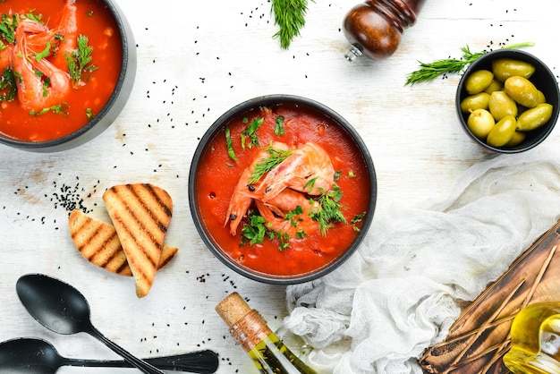 Tomatencremesuppe mit Garnelen in einer schwarzen Schüssel Meeresfrüchtemenü Draufsicht Rustikaler Stil