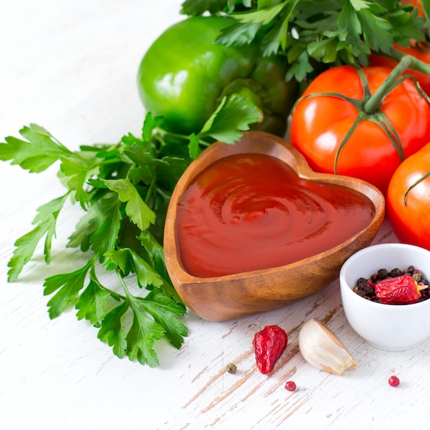 Tomatenketchupsoße in einer hölzernen Schüssel und in den Bestandteilen