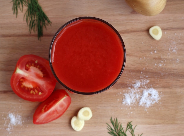 Tomatensaft im Glasglas mit Tomaten-Knoblauch-Salz auf einem Holzbrett