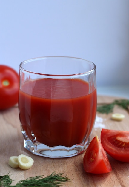 Tomatensaft im Glasglas mit Tomaten-Knoblauch-Salz auf einem Holzbrett