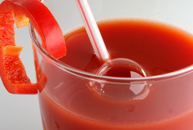 Tomatensaft in einem Glas mit einer Cocktailröhre und einer Scheibe Paprika Nahaufnahme