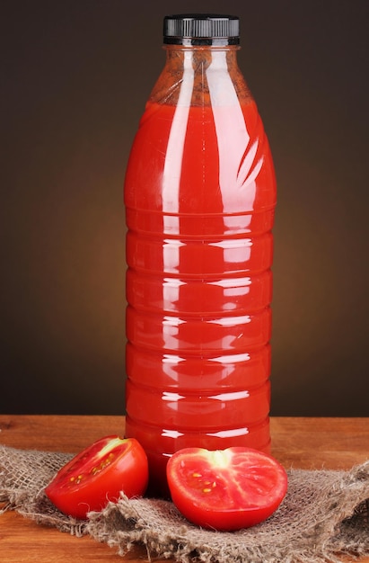 Tomatensaft in Flasche auf Holztisch auf braunem Hintergrund