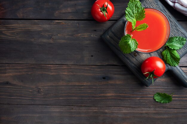 Tomatensaft in Glasgläsern und frischen reifen Tomaten auf einem Zweig.