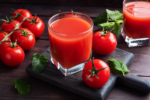 Tomatensaft in Glasgläsern und frischen reifen Tomaten auf einem Zweig