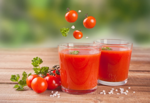 Tomatensaft mit Petersilie auf den Holztisch- und Fliegenkirschtomaten