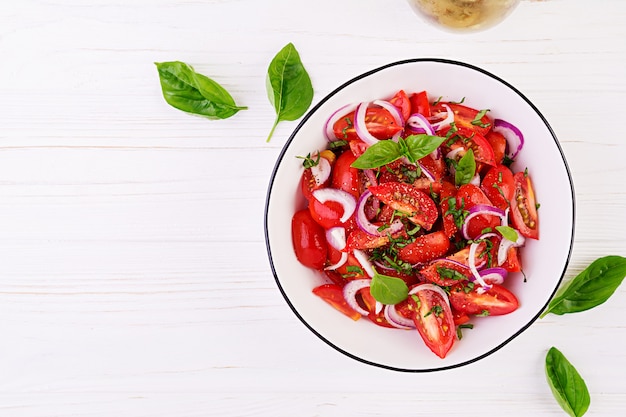 Tomatensalat mit Basilikum und roten Zwiebeln. Konzept gesunde Mahlzeit. Vegane Küche