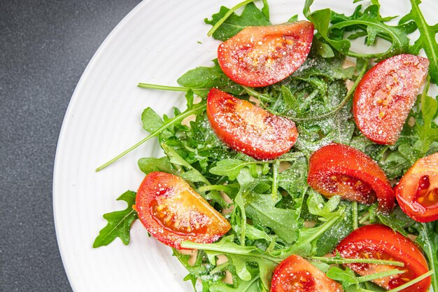 Tomatensalatteller Rucola geriebener Käse Olivenöl gesunde Mahlzeit Snack auf dem Tisch