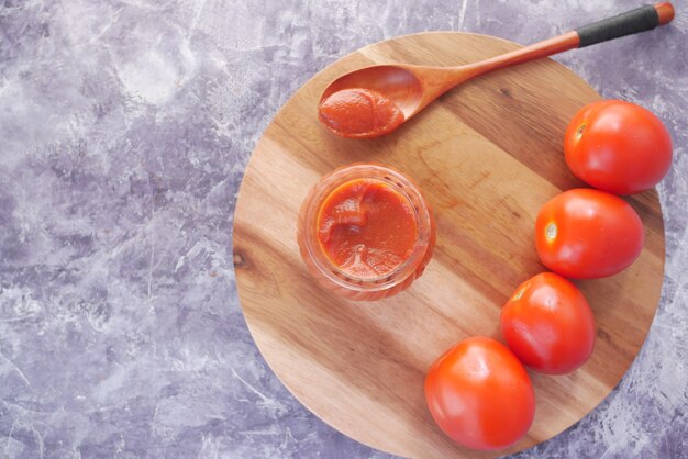 Tomatensauce in einem kleinen Glas mit frischer Tomate auf dem Tisch