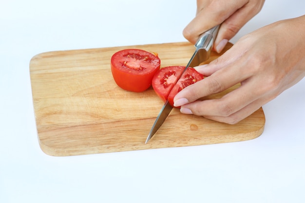 Tomatenscheiben auf hölzernem Block mit Messer gegen weißen Hintergrund