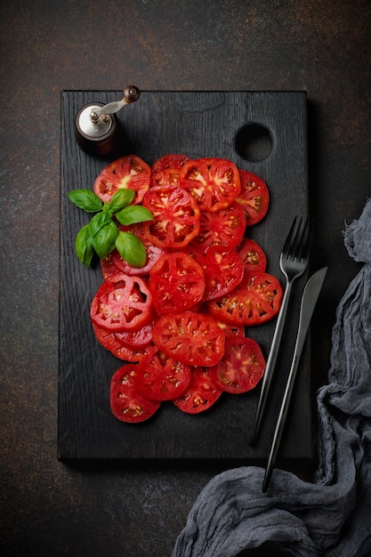 Tomatenscheiben mit Basilikumblättern und Pfeffer