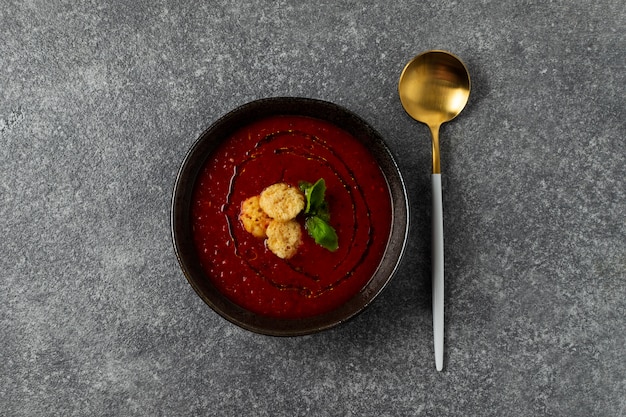 Tomatensuppe in der schwarzen Schüssel auf grauer Steintabelle