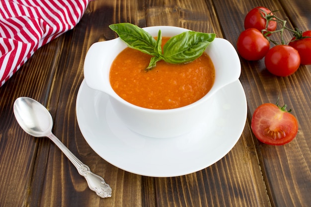 Tomatensuppe in der weißen Schüssel auf dem braunen hölzernen Hintergrund.