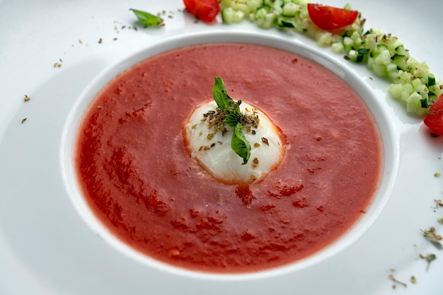 Tomatensuppe in einem weißen Teller auf Holzhintergrund