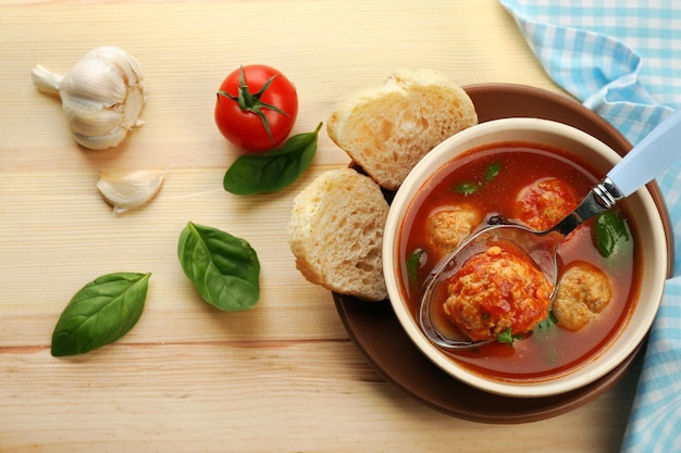 Tomatensuppe mit Fleischbällchen auf Holzlöffel auf Holzhintergrund