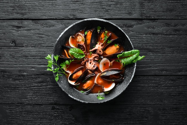 Tomatensuppe mit Meeresfrüchten Muscheln, Muscheln und Tintenfische im alten Hintergrund Draufsicht Freier Kopierbereich