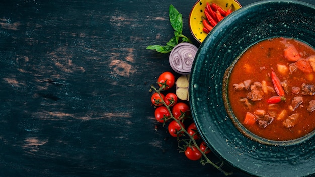 Tomatensuppe mit Rindfleisch und Chilischoten in Chervrniy-Platte Auf einem Holztisch Draufsicht Kopieren Sie Platz