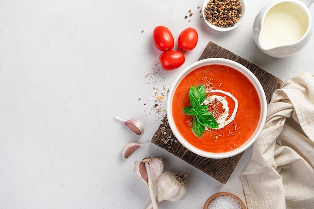 Tomatensuppe mit Sahne auf grauem Hintergrund mit Zutaten