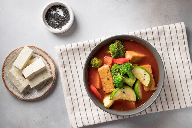 Tomatensuppe mit tofu-käse-brokkoli und zucchini in der draufsicht des veganen lebensmittelkonzepts der schüssel
