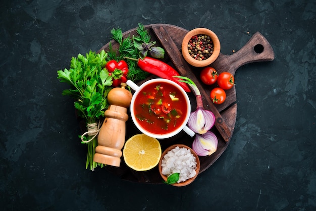 Tomatensuppe mit Zwiebeln, Gurken und Paprika Draufsicht auf schwarzem Hintergrund Freier Platz für Text