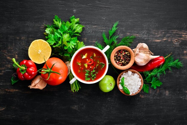 Tomatensuppe mit Zwiebeln, Gurken und Paprika Draufsicht auf schwarzem Hintergrund Freier Platz für Text