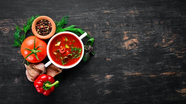 Tomatensuppe mit Zwiebeln, Gurken und Paprika Draufsicht auf schwarzem Hintergrund Freier Platz für Text