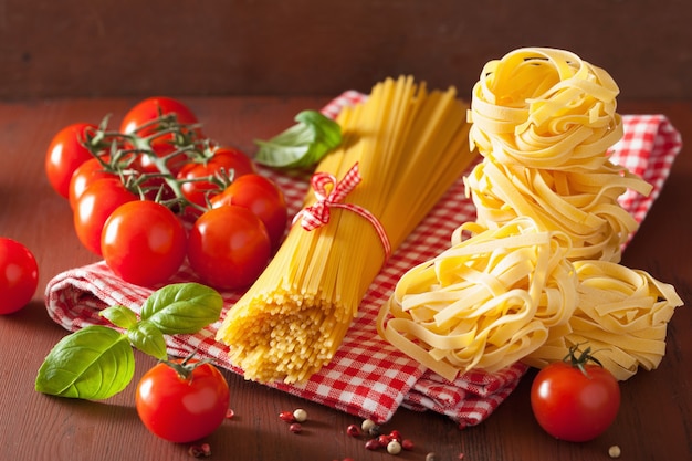 Tomates de albahaca de pasta de espagueti crudo. cocina italiana en cocina rústica