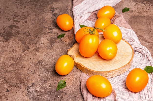 Foto tomates amarelo-laranja em um carrinho de madeira. legumes frescos maduros, produto do fazendeiro orgânico. suporte de madeira, fundo de pedra de mármore, espaço de cópia