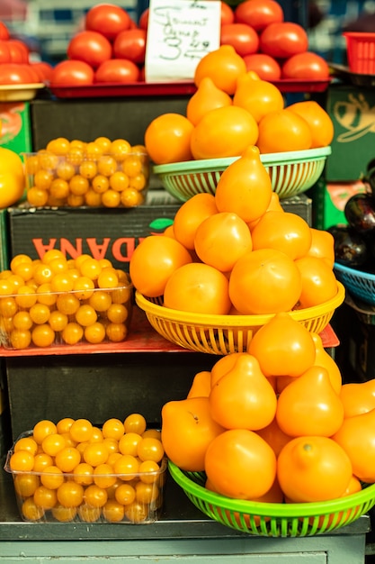 Los tomates amarillos y los tomates cherry del mercado se ponen en la cesta.