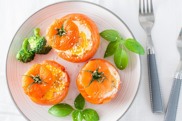 Tomates assados com ovo, brócolis e folhas de manjericão em um prato. Almoço dietético. Vista do topo