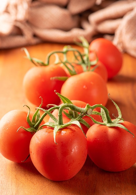 Tomates belos detalhes de tomates vermelhos frescos em galhos sobre foco seletivo de madeira rústica