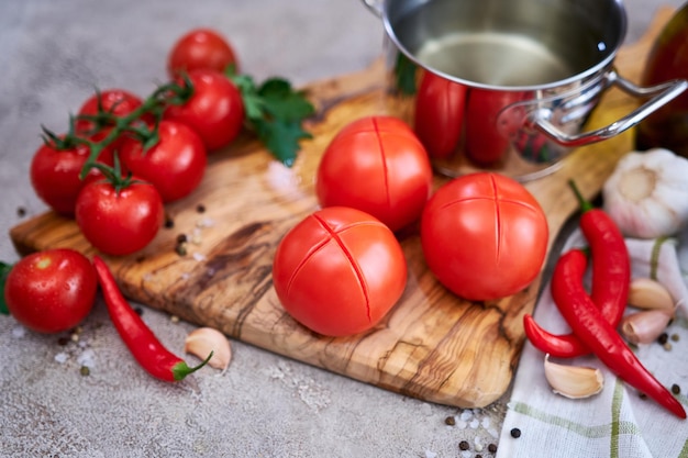 Tomates branqueados na tábua de madeira pronta para descascar na cozinha doméstica