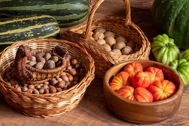 Tomates calabaza y calabacines y cestas con avellanas y nueces apiladas en el suelo