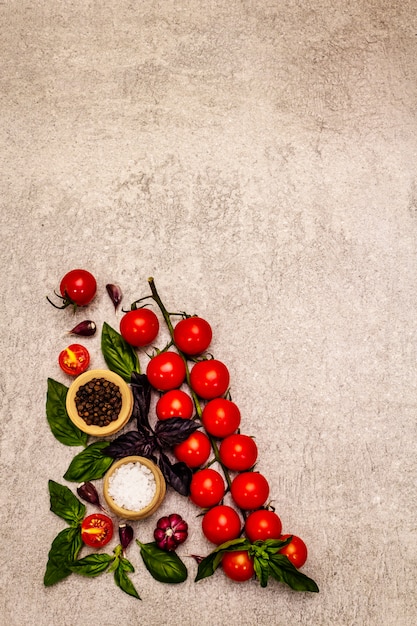 Tomates cereja maduros e especiarias sobre um fundo de pedra