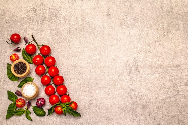 Tomates cereja maduros e especiarias sobre um fundo de pedra