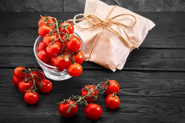 Tomates cereja orgânicos frescos em um fundo escuro, entrega de comida. Copie o espaço.