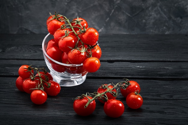 Tomates cereja orgânicos frescos em uma superfície escura, entrega de comida. Copie o espaço.