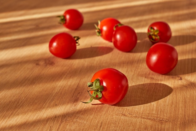 Tomates cereja vermelhos frescos em uma superfície de madeira na luz do dia.