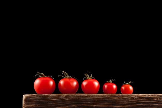 Tomates cereja vermelhos pequenos em uma velha placa de madeira marrom