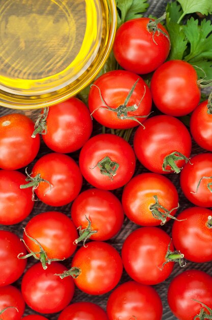 Tomates cherry, aceite de oliva y hierbas sobre un fondo de madera. Fondo vegetal Vista superior